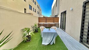 A small patio with a table and chairs, surrounded by potted plants and a wooden fence. - Rd Jade apt Neuf Avec Jardin Proche des Commodit s (La Marsa)