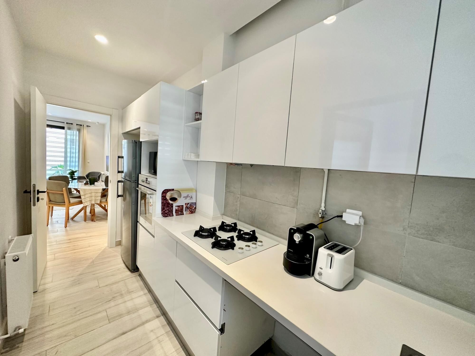 A modern kitchen with white cabinets, a gas stove, a coffee maker, and a toaster.
