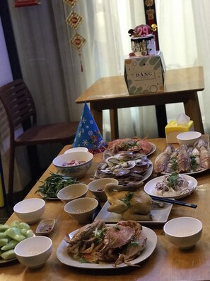 A dining table with various dishes, including seafood and vegetables, and several bowls and cups. - TEDDY 108 HOMESTAY & CAFE - GRAND WORLD PHU QUOC (Phu Quoc)