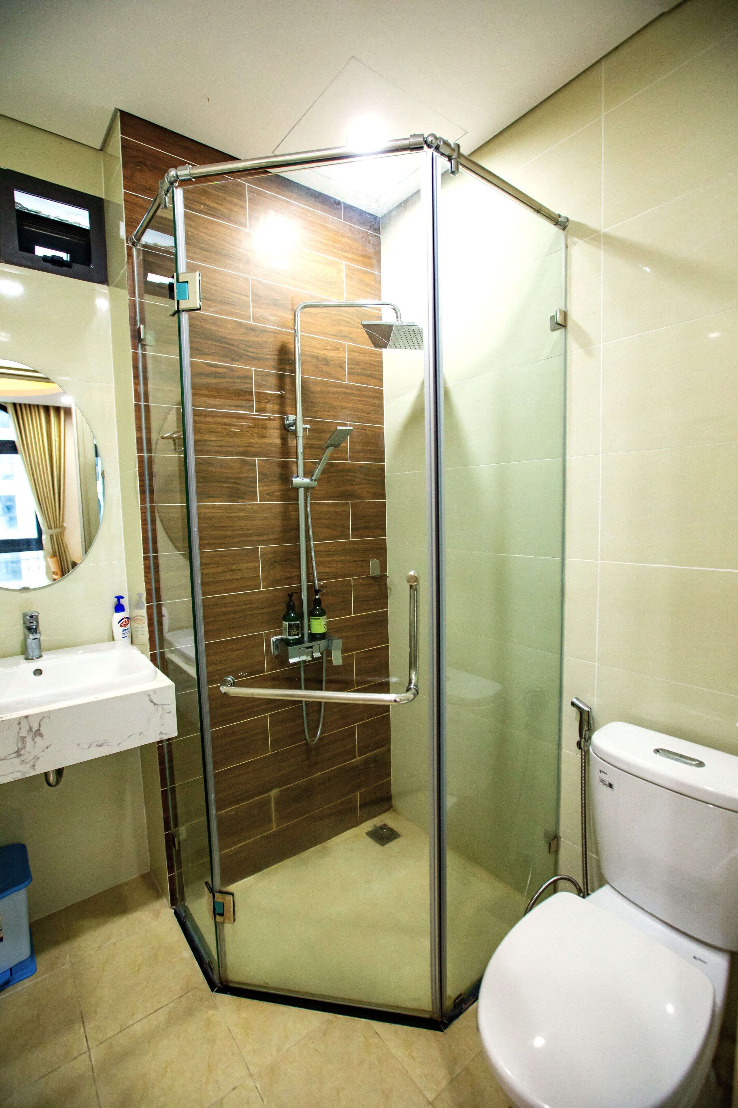 Un baño moderno con ducha envuelta en vidrio, inodoro blanco y lavamanos de mármol.