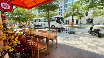 Un espace extérieur aménagé avec une table et des chaises, un parasol rouge et un scooter garé.