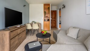 A living room with a TV, a dining area with chairs, a small table with a laptop, and a sofa. - Elli Down Town Apartment Karma (Rodos)