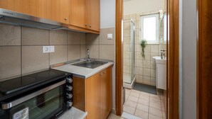 A compact kitchen with a built-in oven, a sink, and wooden cabinets. - Elli Down Town Apartment Karma (Rodos)