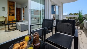 A balcony with a table set for breakfast, a sofa, and a chair. - Elli Down Town Apartment Karma (Rodos)