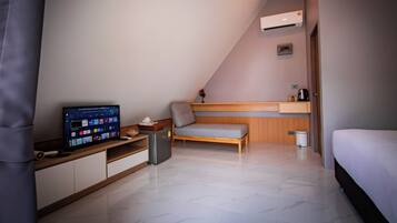 A modern bedroom with a bed, a TV, a small desk, and a bench.