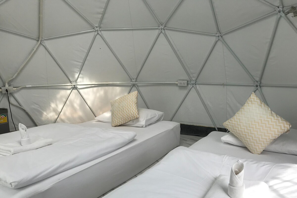 A tent-style room with two beds, each with a pillow and a folded towel.