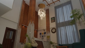 Eine Lobby mit einem hölzernen Empfangstresen, einer Buddha-Statue, einer Kristallleuchter und einem grünen Sessel.