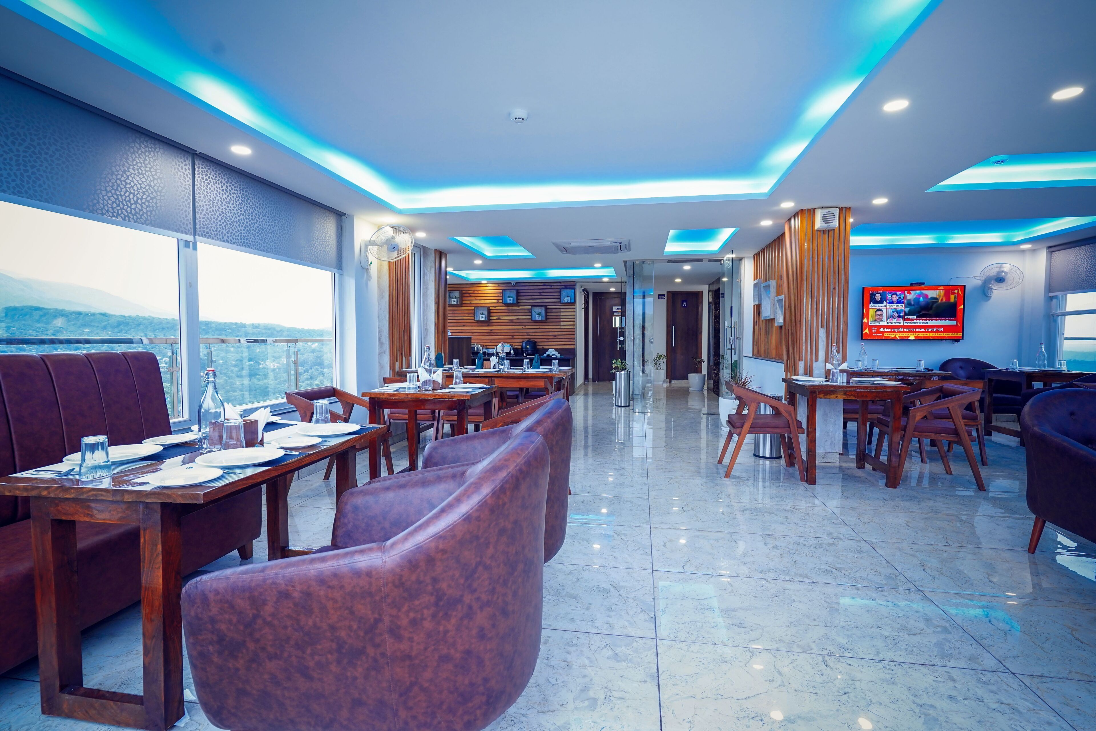 Un restaurant moderne avec un plafond haut, un éclairage bleu et une vue sur les montagnes.