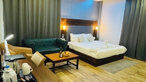 Ein Hotelzimmer mit Bett, Sofa, Couchtisch und Schreibtisch mit einem Tablett Frühstücksgebäck.