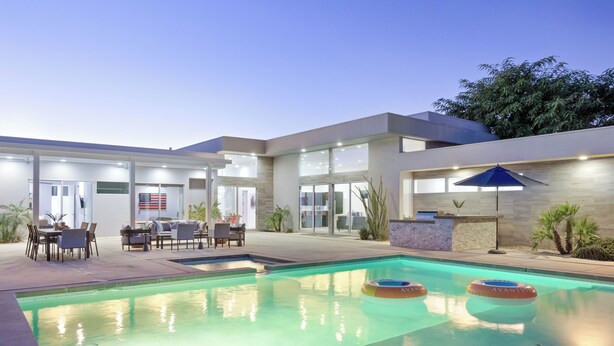 Uma casa moderna com piscina, móveis de exterior e um espaço de varanda.