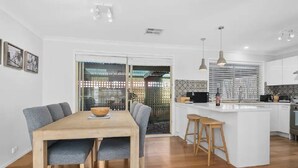 Una cocina moderna con una isla central, mesa de comedor de madera y taburetes de bar.