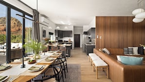 Une cuisine moderne avec des meubles de couleur sombre, un îlot central et un coin repas comprenant une longue table et des chaises.