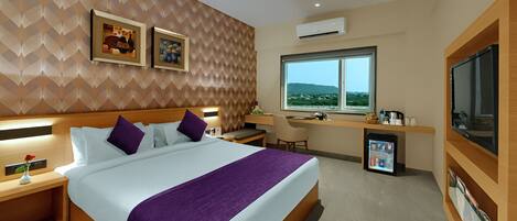 Quarto de hotel moderno com uma cama grande, uma escrivaninha, uma cadeira, uma televisão e uma janela com vista.