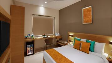 A modern hotel room with a large bed, a desk, a chair, a television, and a ceiling fan.