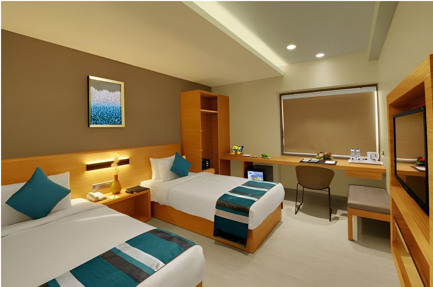A hotel room with two beds, a desk, a chair, a TV, and a large mirror.