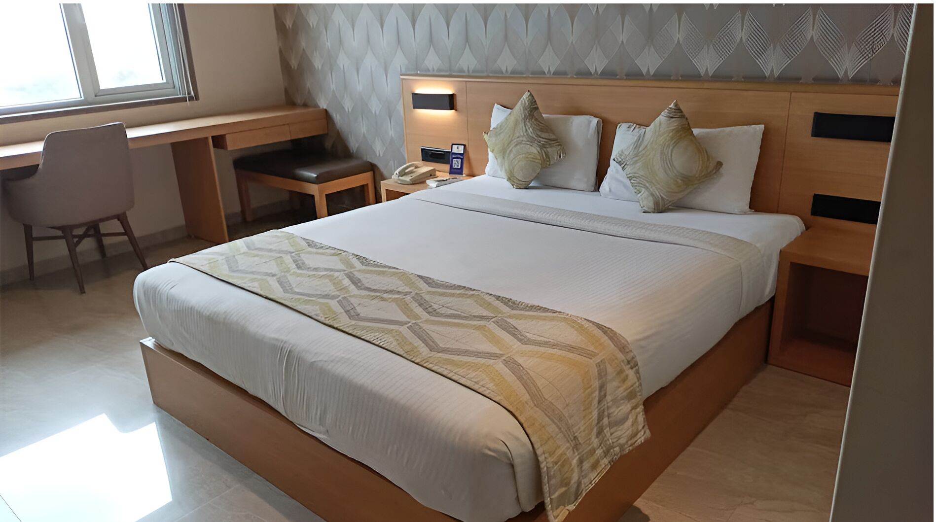 Een hotelkamer met een groot bed, een bureau en een stoel.