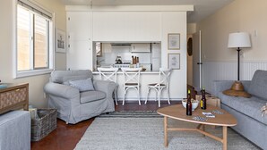 A compact living space with a kitchenette, a grey sofa, a dining area, and a ceiling fan. - Patio + Sunset Views + Beach Days | Right on the Water | Bay View 2 (San Diego)