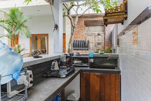 A compact kitchen with a sink, stove, and various utensils. - Canggu Kayuma House (Canggu)