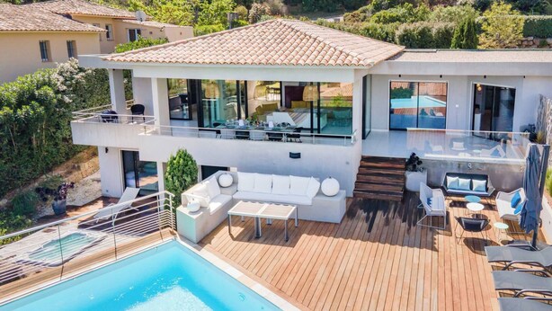 Une villa moderne dotée d’une piscine, d’un espace extérieur aménagé et d’une terrasse offrant une vue sur le paysage environnant.