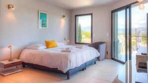 Une chambre moderne avec un grand lit, une table de chevet, un bureau et une chaise. Il y a une fenêtre donnant sur l’extérieur.