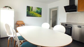 A modern kitchen with a white table, chairs, and a stove. - Holiday Home in Lichtenau with Garden Bliss (Lichtenau / OT Auerswalde)