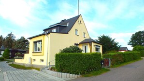 A two-story residential building with a sloped roof, a small front porch, and a well-maintained hedge. - Holiday Home in Lichtenau with Garden Bliss (Lichtenau / OT Auerswalde)