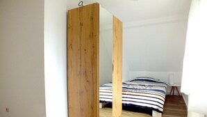 Un dormitorio con una cama, un armario de madera y una mesita blanca.