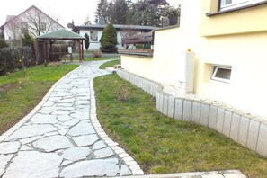 A stone pathway leading to a wooden gazebo in a residential area. - Holiday Home in Lichtenau with Garden Bliss (Lichtenau / OT Auerswalde)
