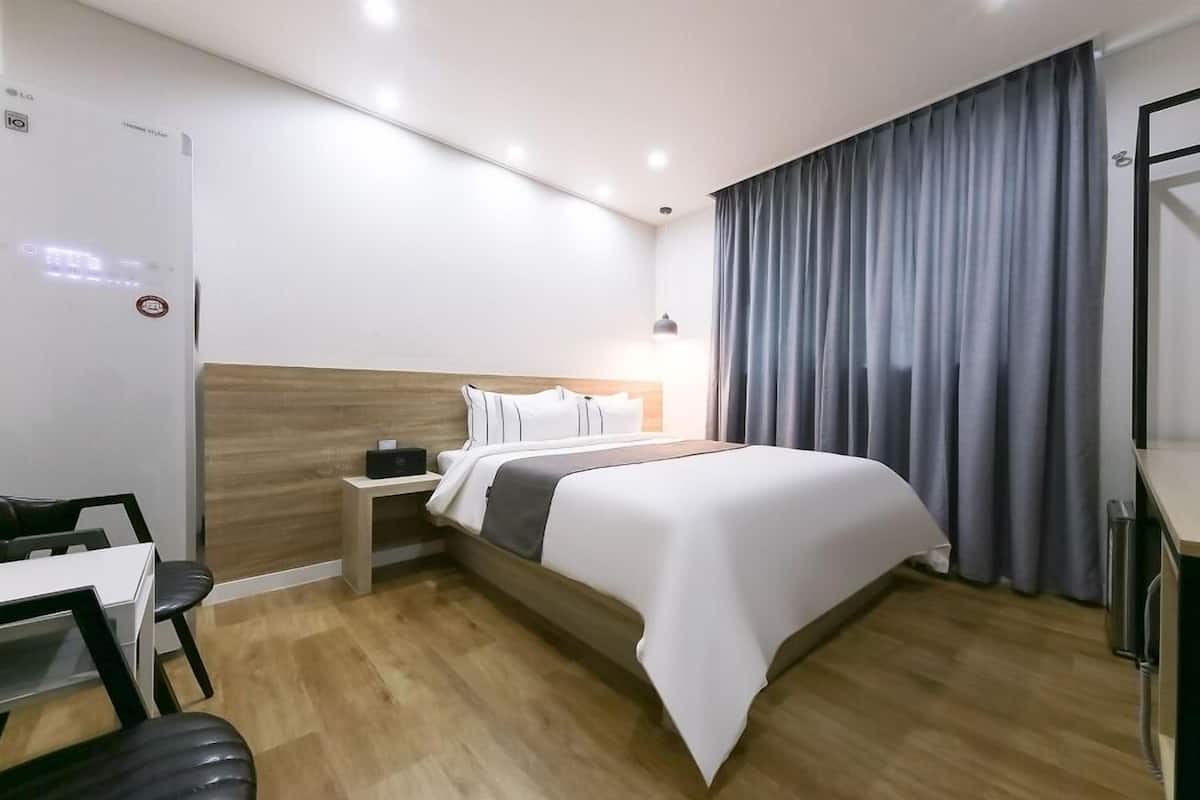 Une chambre d’hôtel comprenant un lit, une table de chevet, une lampe et un bureau avec une chaise.