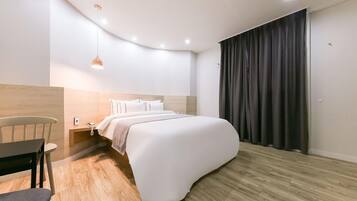 A modern bedroom with a curved bed, a wooden nightstand, a desk, and a chair.