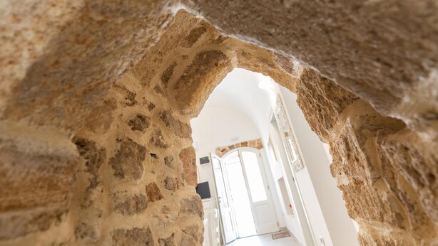 An arched stone doorway leading into a room with white walls and a door in the background. - Appartamento Misya - Felline (Felline)