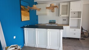 A kitchen with white cabinetry, a black countertop, and a blue wall. There are two hanging baskets and a sign on the wall.