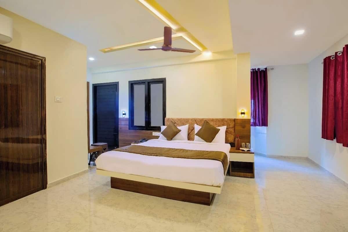A bedroom with a large bed, a ceiling fan, and a nightstand with a lamp.