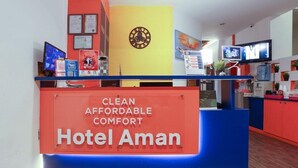 Un mostrador de recepción de hotel con un cartel que dice "CLEAN AFFORDABLE COMFORT Hotel Aman".