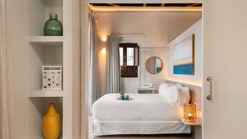 A neatly arranged bedroom with a bed, bedside table, and a shelf with decorative items.