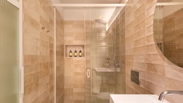 A modern bathroom with a glass-enclosed shower, a white sink, and a tiled wall.