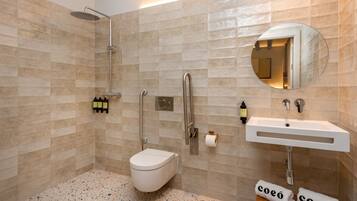 Un baño moderno con ducha, inodoro, lavamanos y espejo.