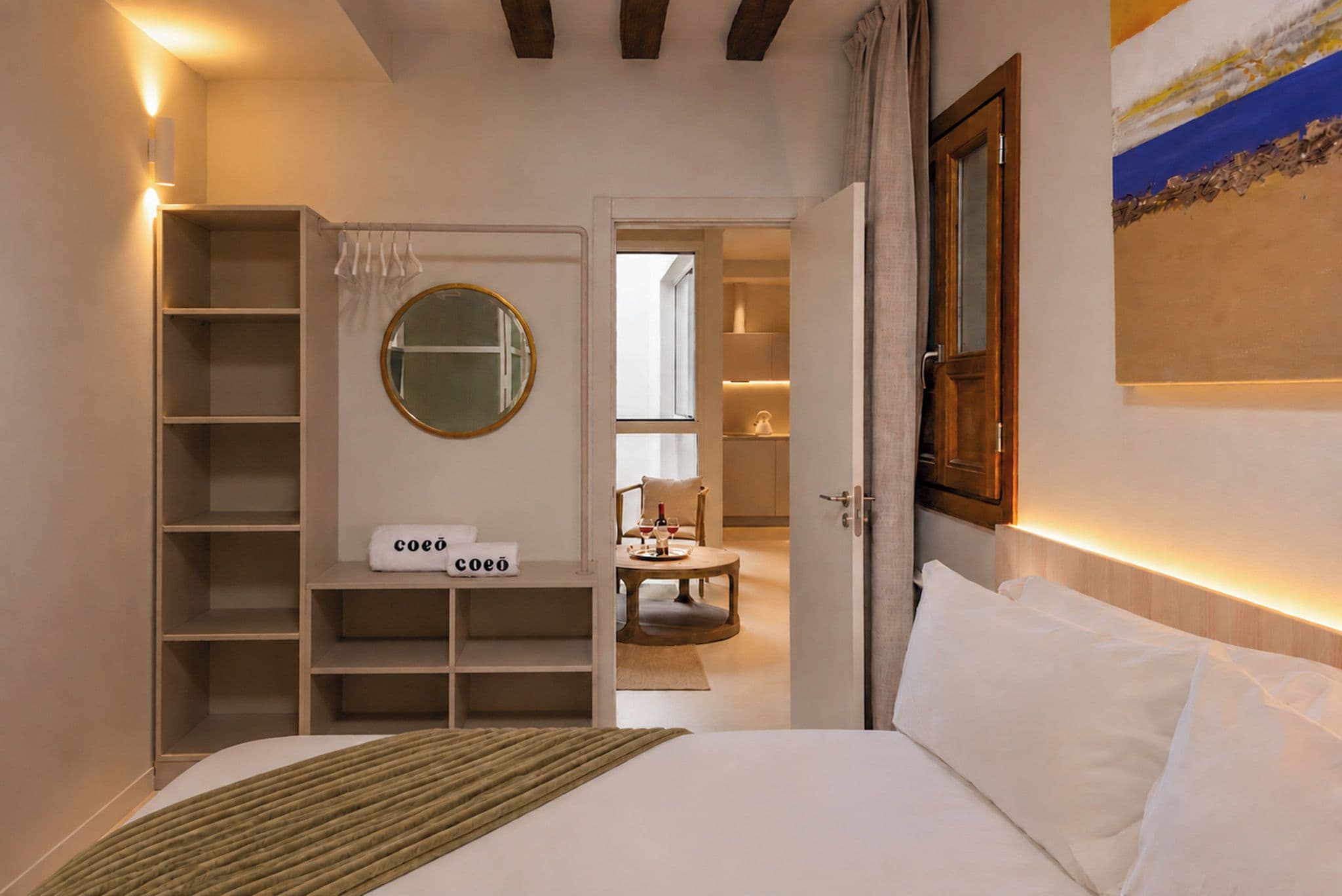 A bedroom with a bed, a wardrobe, a mirror, and a view into another room.