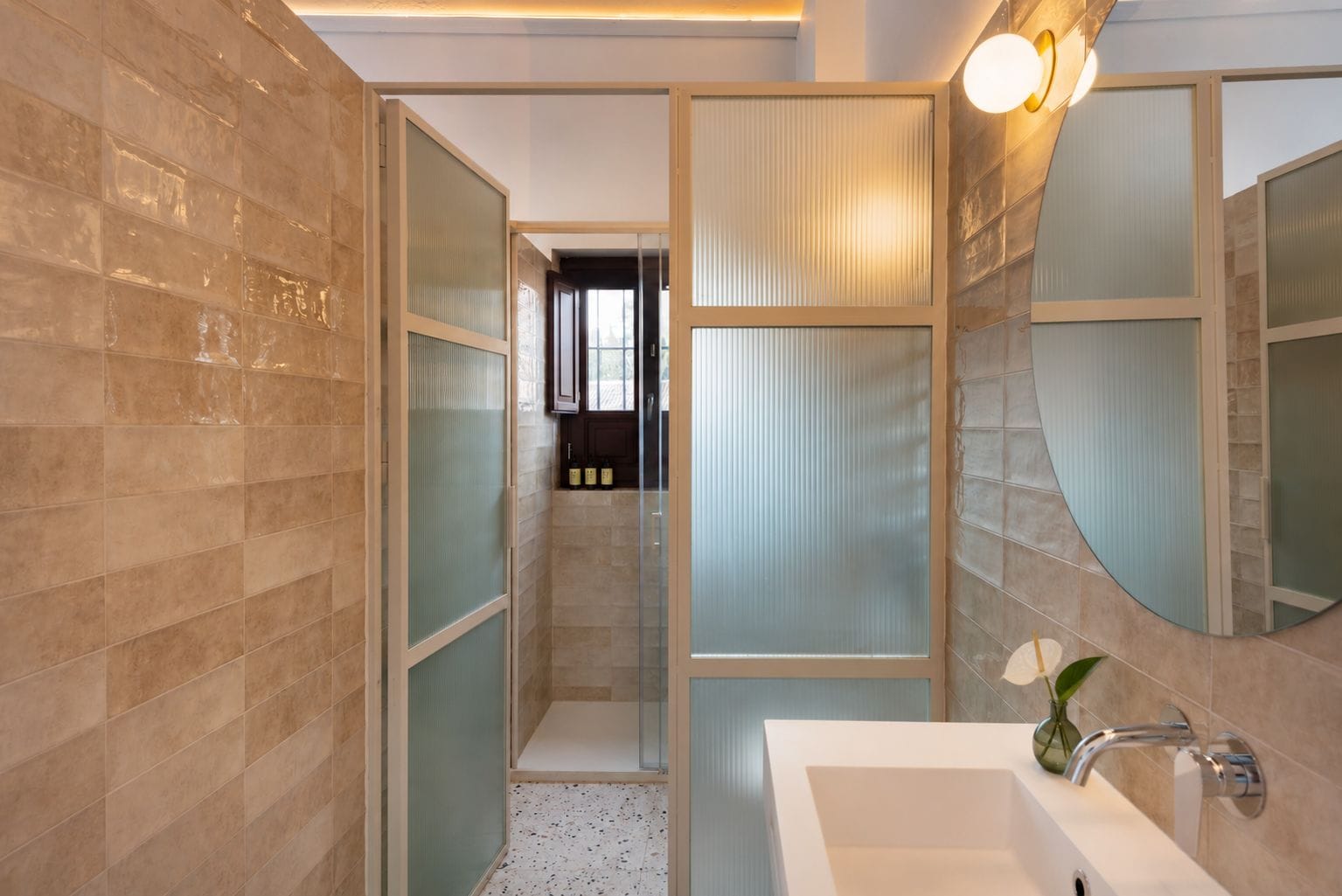 Un baño moderno con un espejo grande, un lavabo y una zona de ducha.