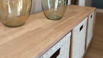 Twee glazen vazen op een houten tafel met witte manden eronder.