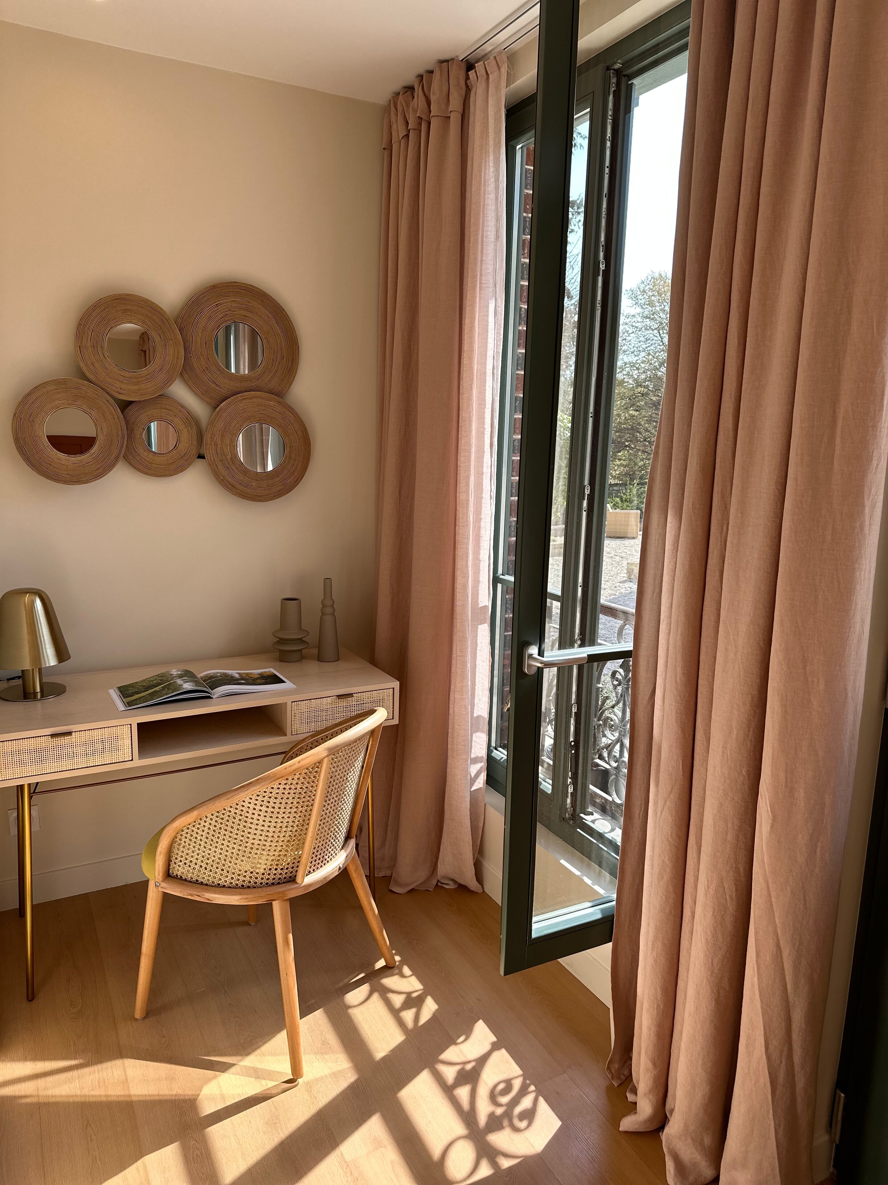 Habitación con escritorio, silla y ventanas amplias con cortinas.