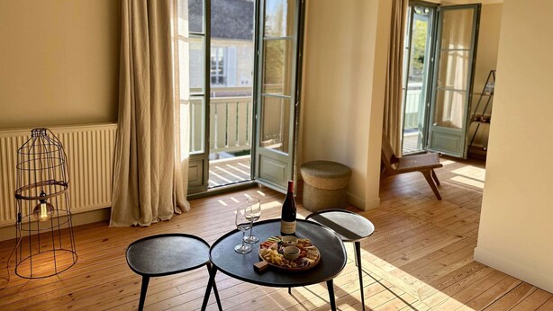 A dining area with a table set for two, a wine bottle, and a fruit platter. - LA DEMEURE (Précy-sur-Oise)