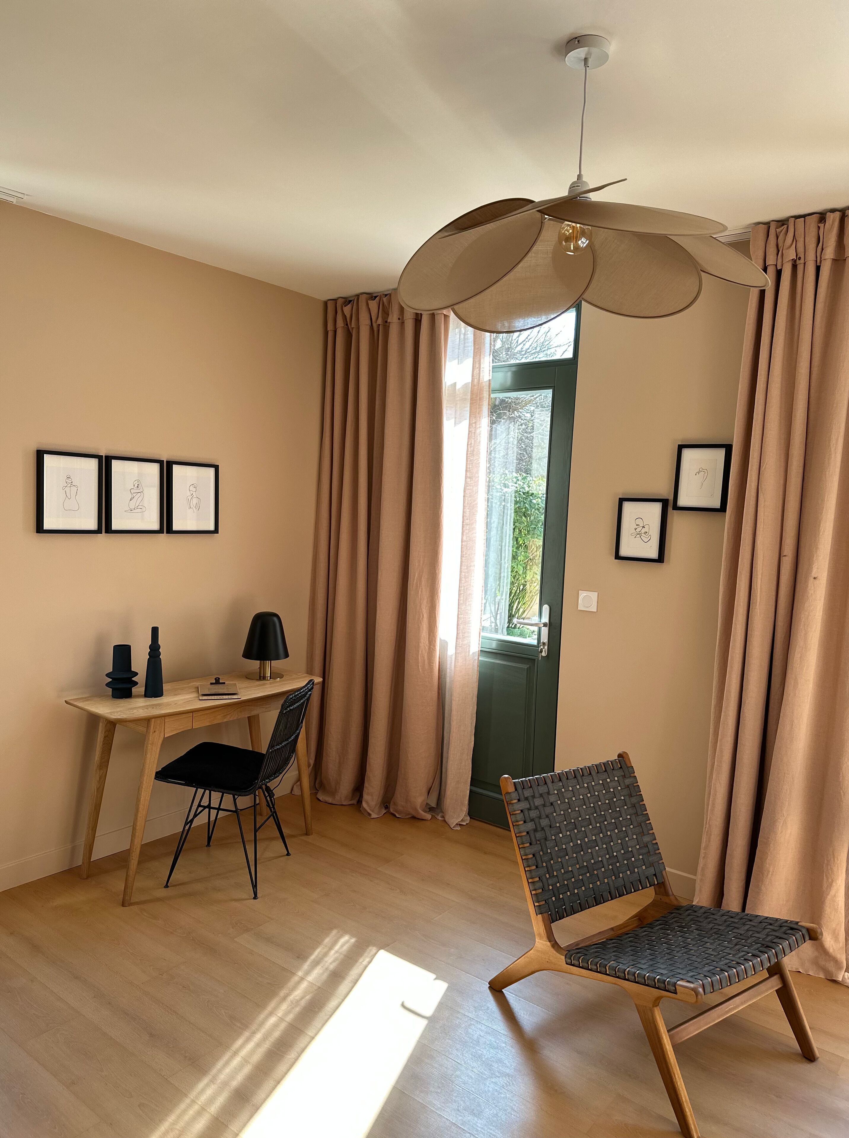 A room with a desk, two chairs, a lamp, and framed pictures on the wall.