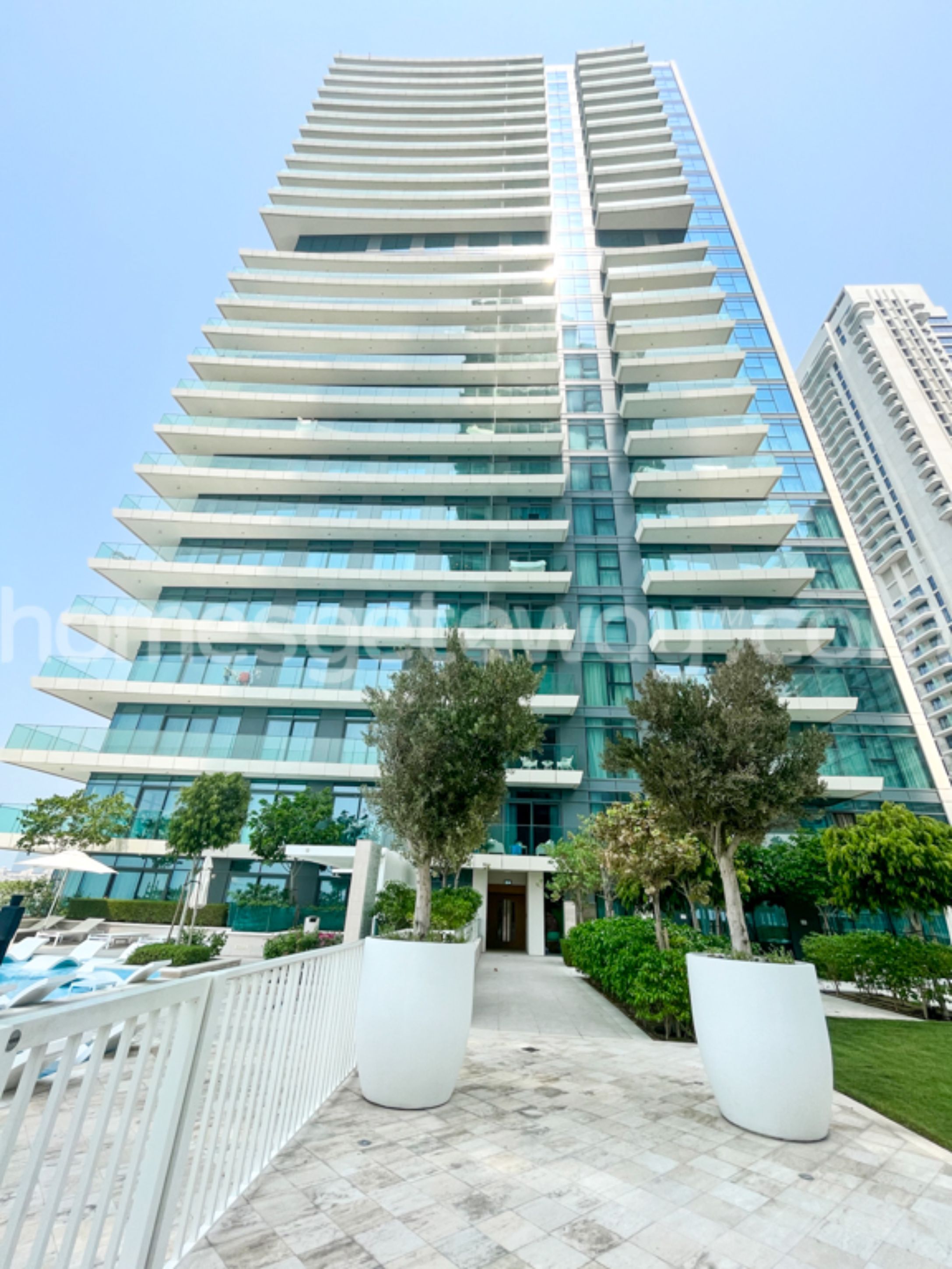 A tall, modern building with a glass facade and multiple balconies.