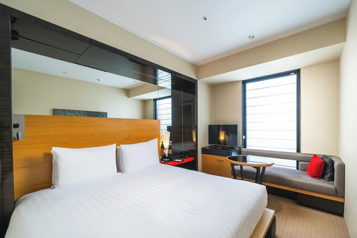 Ein Hotelzimmer mit einem großen Bett, einem Fernseher, einer Couch und einem Schreibtisch mit Stuhl.