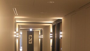 A hotel hallway with carpeted floors, doors, and wall-mounted lights. - Koko Hotel Premier Kanazawa Korinbo (Kanazawa)