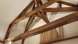 Quarto com cama, vigas de madeira e cabeceira.