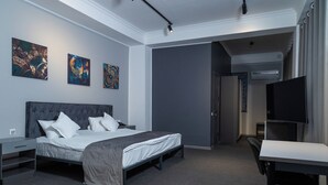 A modern hotel room with a bed, a desk, and a TV. There are three artworks on the wall. - THE TIME HOTEL (Tashkent)