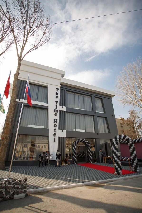 A modern hotel building with a checkered entrance area, a flag, and a sign reading "The Time Hotel." - THE TIME HOTEL (Tashkent)