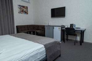 A hotel room with a bed, a sofa, a desk, a chair, and a TV mounted on the wall. - THE TIME HOTEL (Tashkent)